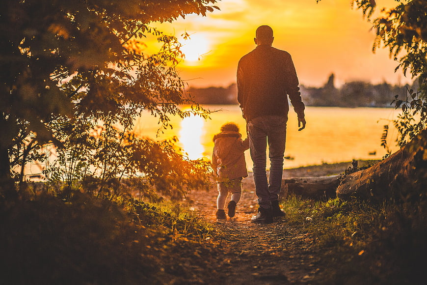 Father and Child Walking by Lake at Sunset
