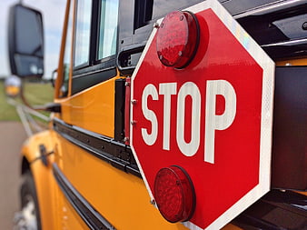 Close-up of a school bus stop sign with red lights