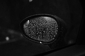 Black and white car side mirror with raindrops at night