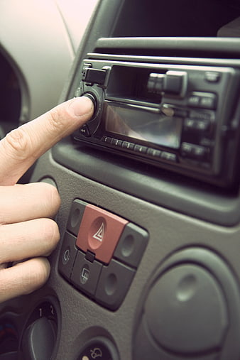 Close-up of hand adjusting car radio volume knob