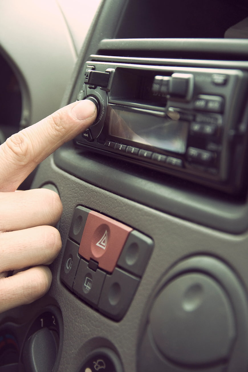 Close-up of hand adjusting car radio volume knob