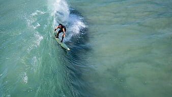 Surfer riding a wave from an aerial perspective