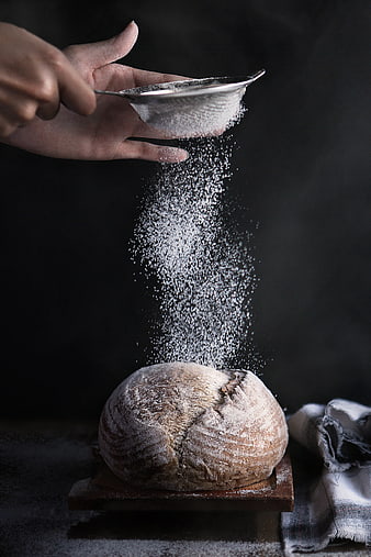 Hand Sifting Flour Over Rustic Artisan Bread Loaf