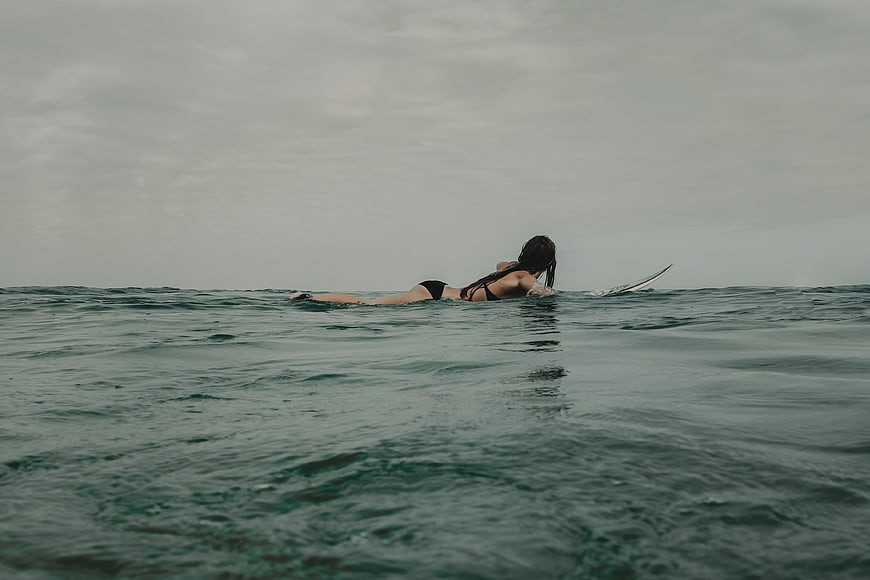 Woman paddling surfboard in ocean waves