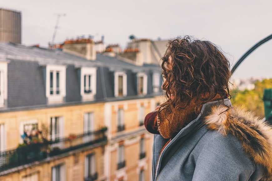 Woman with curly hair looking at Parisian rooftops