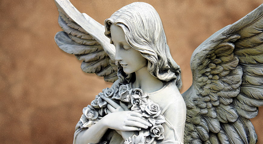 Close-up of a white stone angel statue holding roses