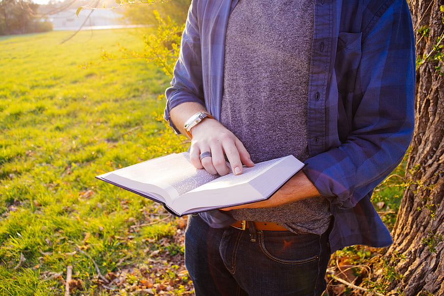 Man Reading Book Outdoors in Park at Sunset