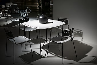 Modern minimalist dining table and chairs with dramatic shadows