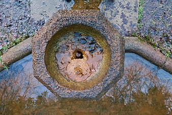 Top-down view of old stone fountain with water reflection