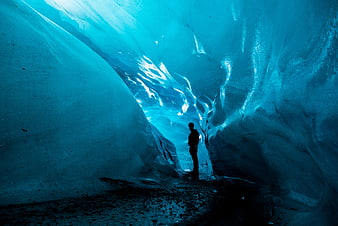 Silhouette of Man Standing Inside Blue Ice Cave