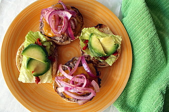 Overhead view of mini burgers with avocado and red onions