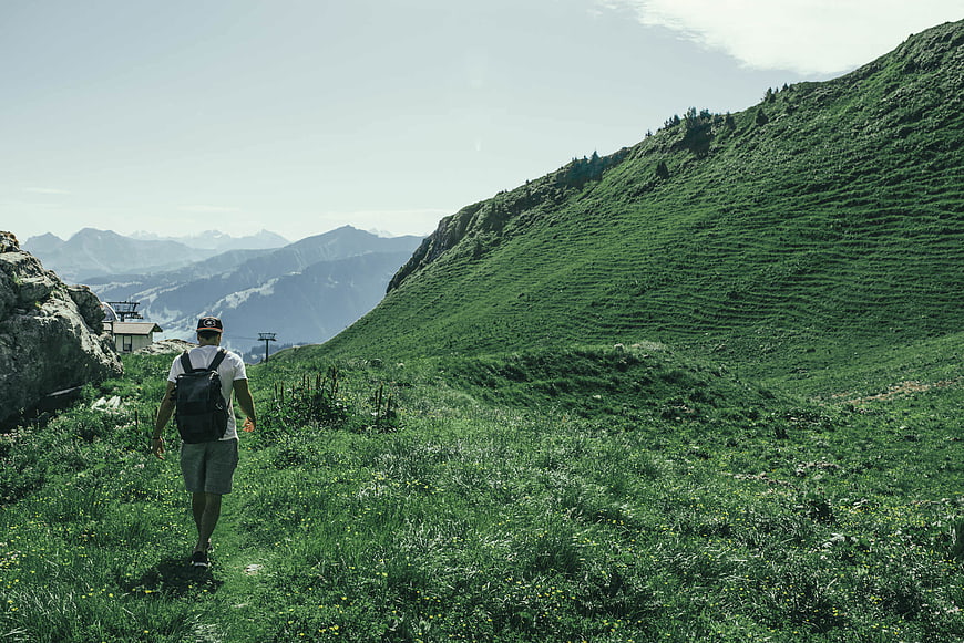 Man hiking on a green mountain trail in the Swiss Alps