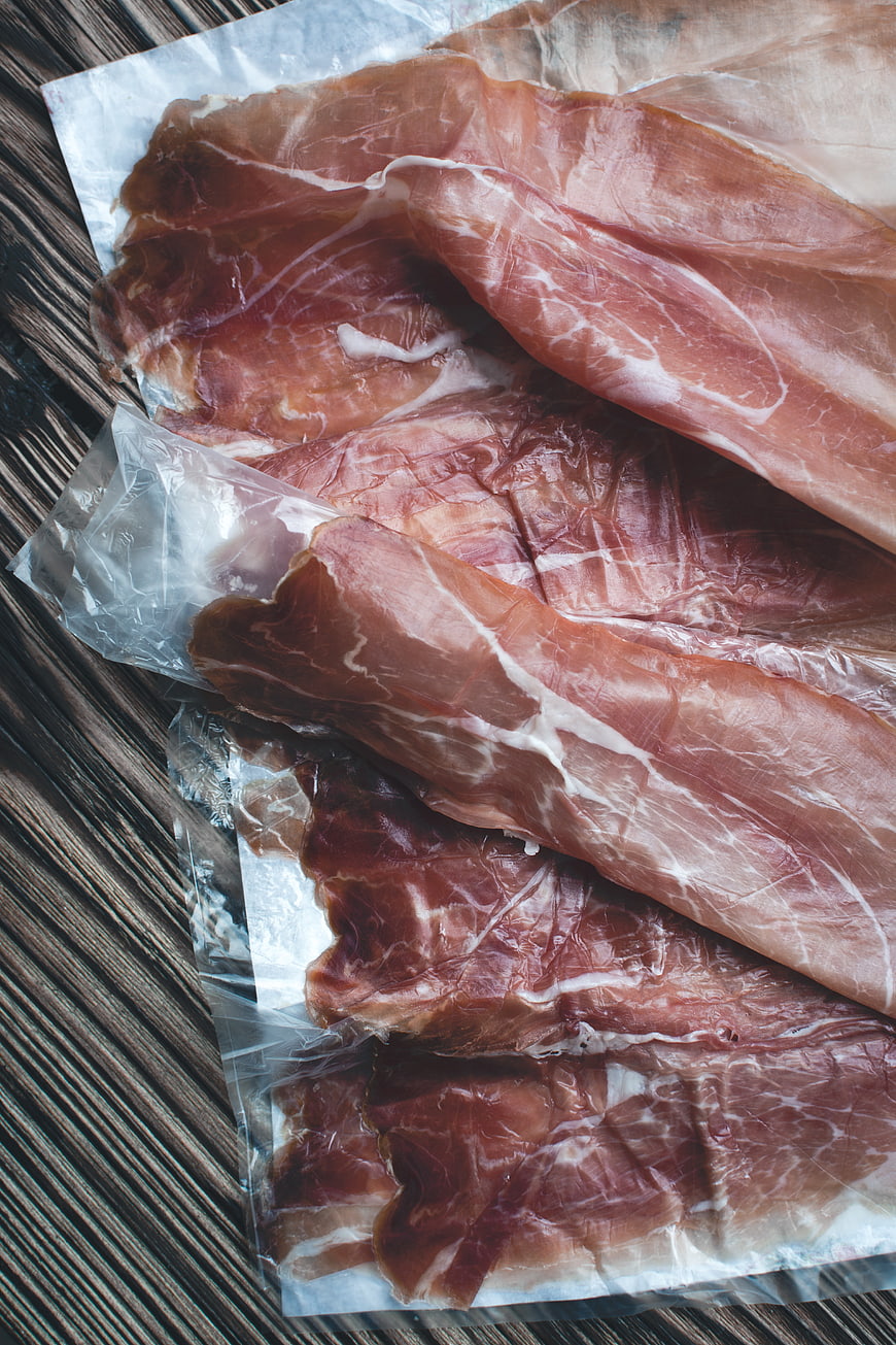 Slices of Prosciutto Crudo on Wooden Table