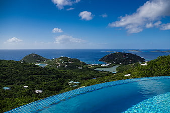 Infinity pool overlooking tropical ocean and lush green hills