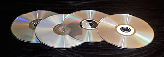 Four blank optical discs on dark wood background