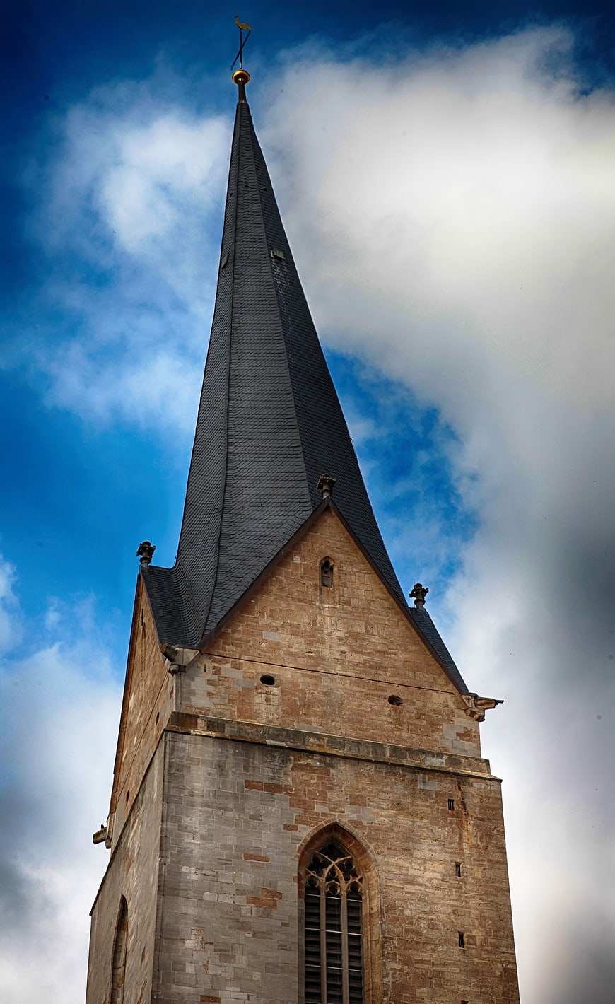 Low angle view of medieval church steeple against blue sky