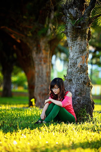 Young Woman Sitting Under Tree in Park