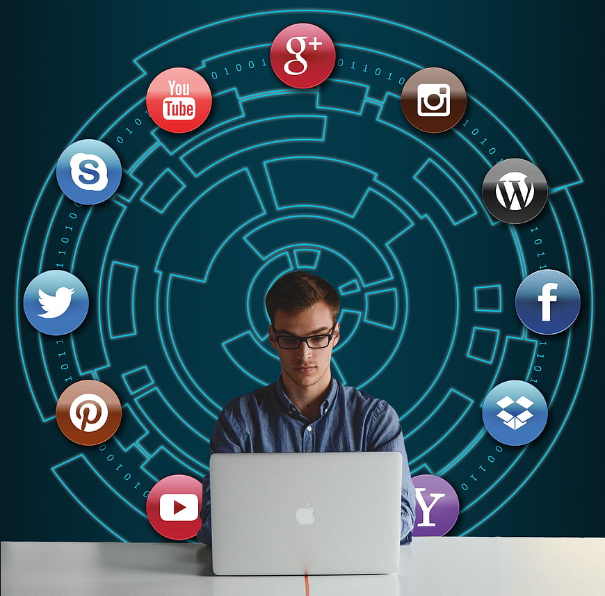 Man working on laptop surrounded by social media icons and digital network