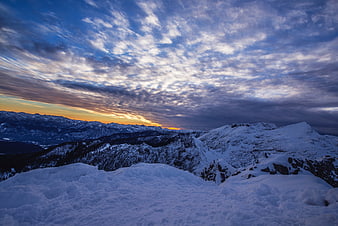 Snowy Mountain Ridge at Sunset with Dramatic Clouds
