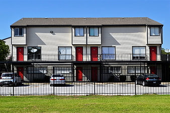 Two-story apartment complex with red doors and black fence