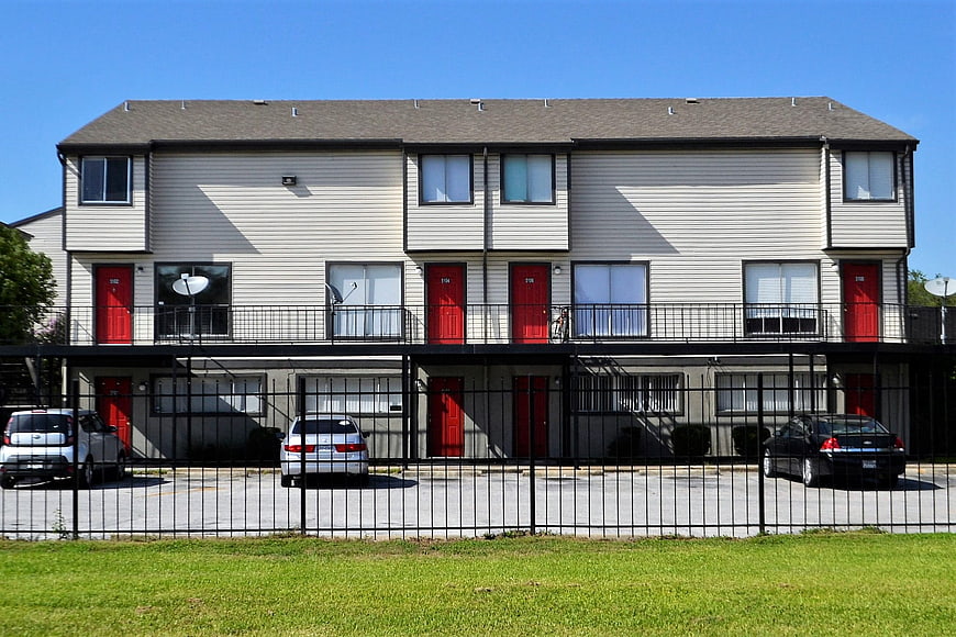 Two-story apartment complex with red doors and black fence