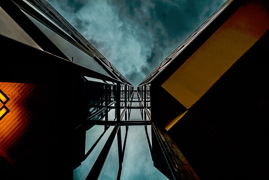 Low angle view of modern glass skyscrapers against cloudy sky