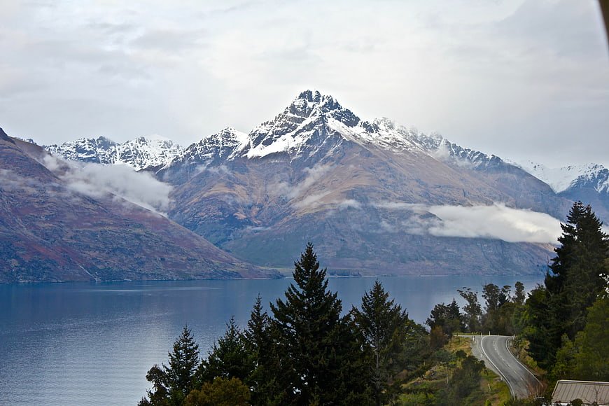 Snow-capped mountain peak overlooking a lake and winding road