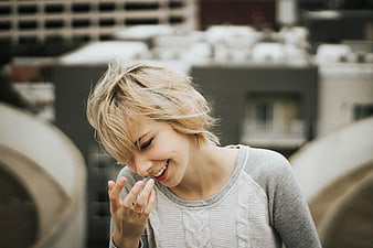 Laughing blonde woman with short hair on urban rooftop