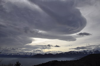 Dramatic storm clouds over snow-capped mountain range