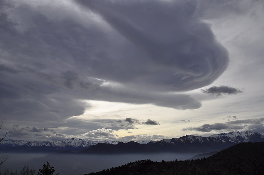 Dramatic storm clouds over snow-capped mountain range