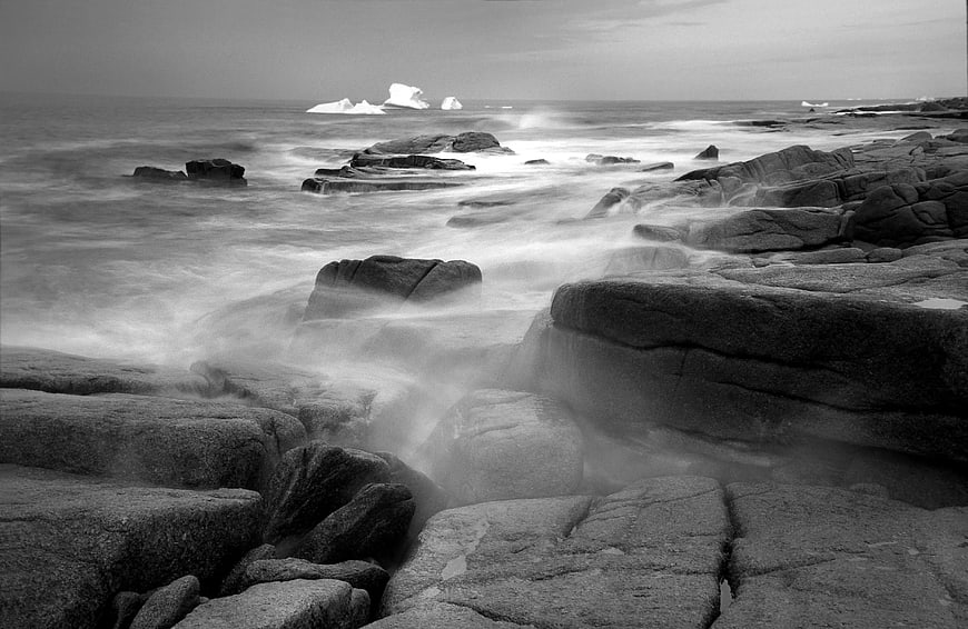 Black and white long exposure rocky coastline with icebergs