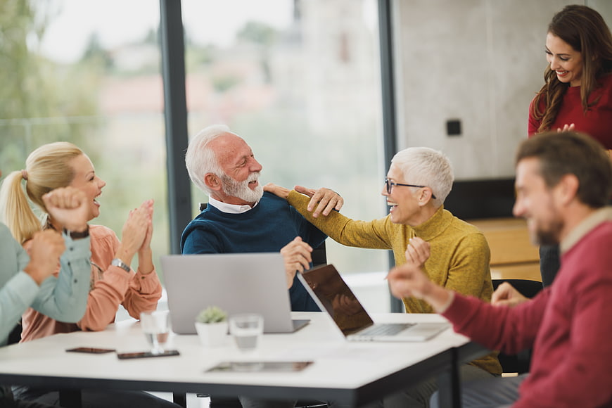 Happy multi-generational team celebrating success in modern office