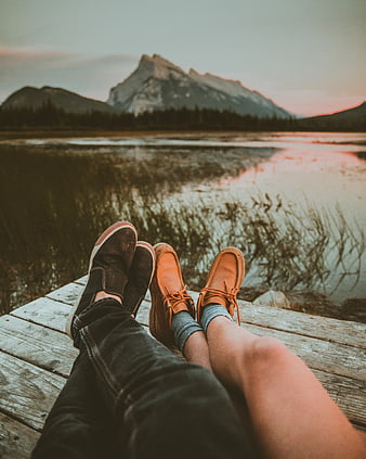 Couple relaxing on dock with mountain lake sunset view