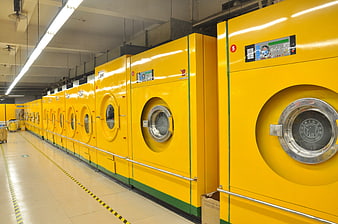 Row of yellow industrial washing machines in commercial laundry facility
