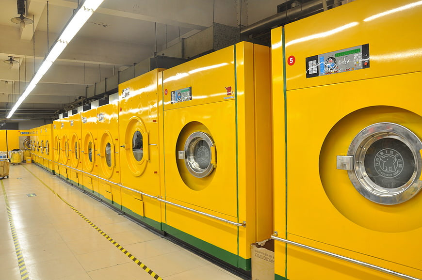 Row of yellow industrial washing machines in commercial laundry facility