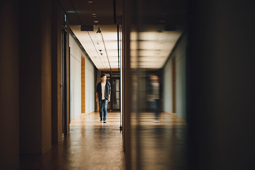 Man Walking in Modern Hallway with Reflection