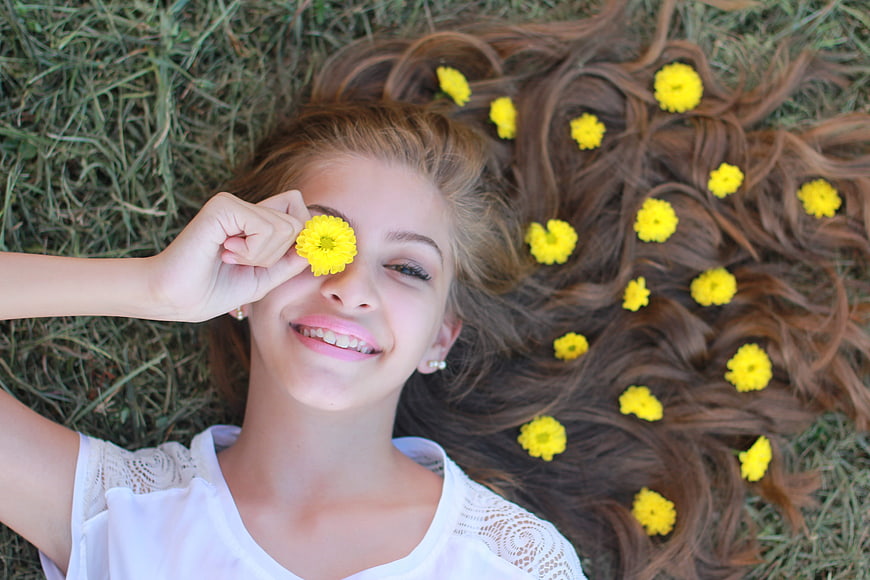 Teenage girl lying on grass with yellow flowers in hair