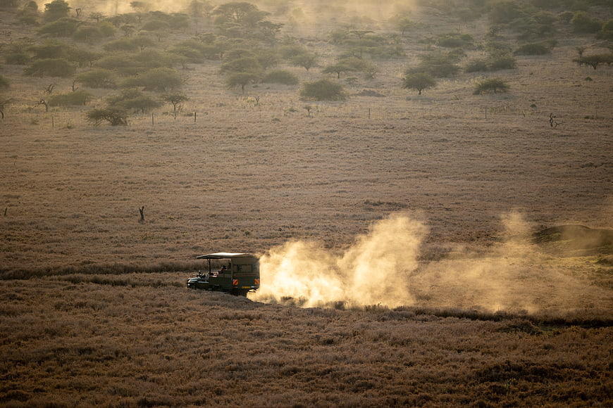 Safari Jeep Driving Through Dusty African Savanna Landscape