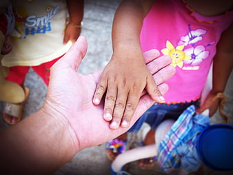 Close-up of adult hand holding child's hand outdoors