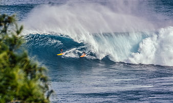 Surfers riding a massive ocean wave with dramatic spray