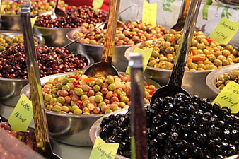 Variety of marinated olives in metal bowls at a market stall