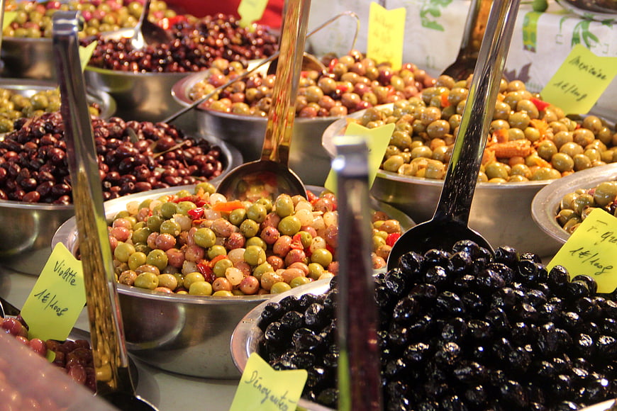 Variety of marinated olives in metal bowls at a market stall