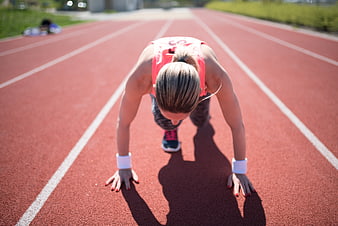 Female Athlete In Starting Position On Outdoor Running Track