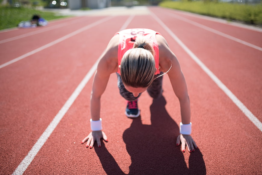 Female Athlete In Starting Position On Outdoor Running Track