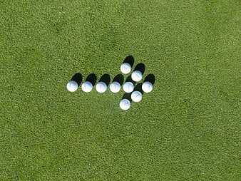 Golf Balls Arranged In Arrow Shape On Green Grass