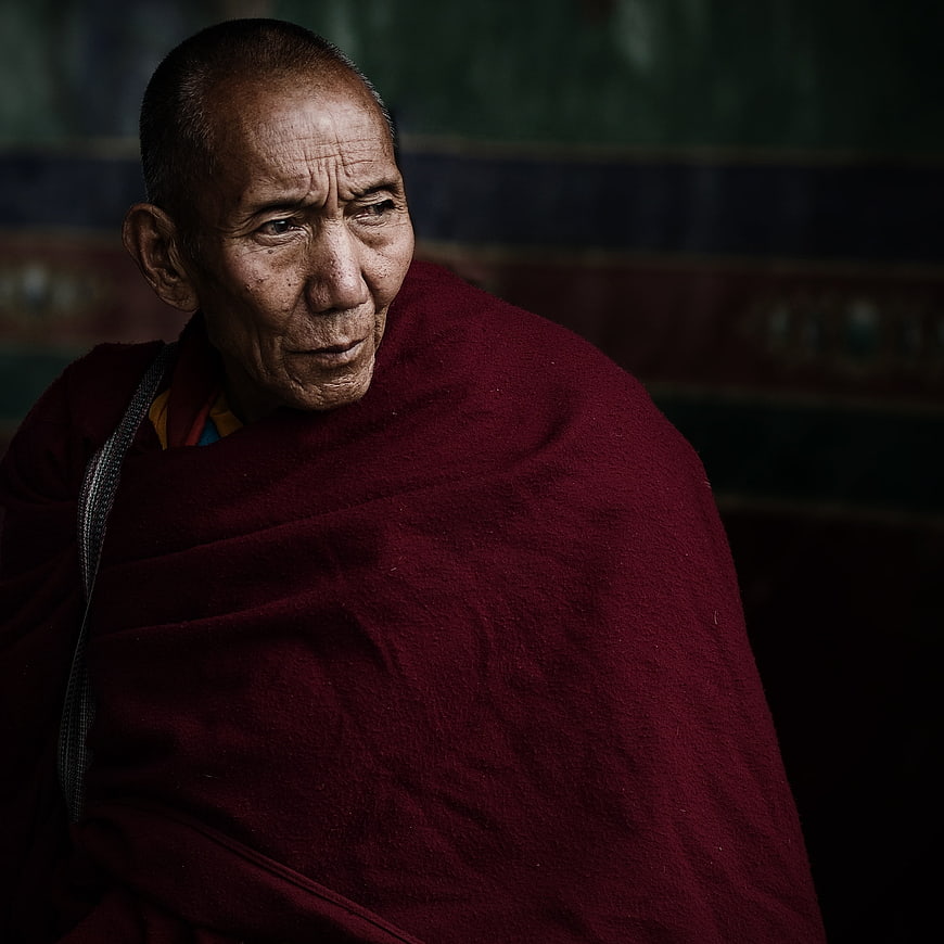 Portrait of elderly Tibetan monk in maroon robes