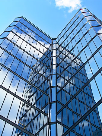 Low angle view of modern glass skyscraper reflecting blue sky