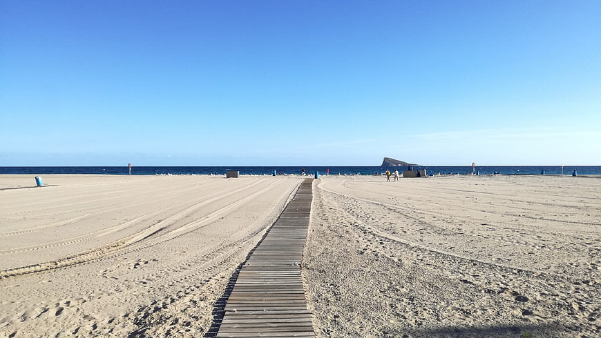 Wooden boardwalk path leading to sandy beach and blue sea