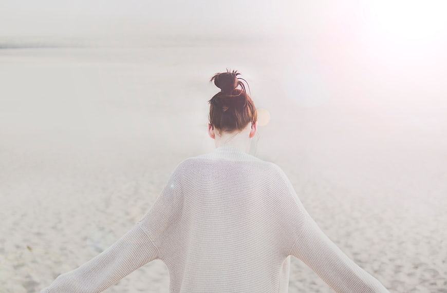 Woman in White Sweater Standing on Beach Facing Sun