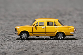 Yellow Fiat 125p Toy Car on Gravel Surface